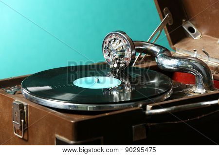 Gramophone with vinyl record on table on green background