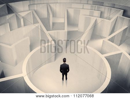A confused businessman standing in the center of a maze surrounded with walls of the labyrinth