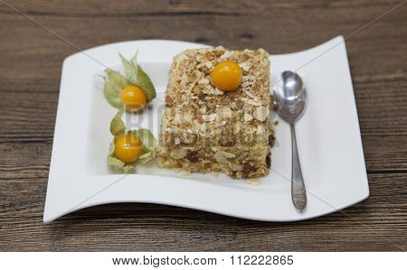Fresh delicious diet cake with berry Physalis at Dukan Diet on a porcelain plate with a spoon on a wooden background