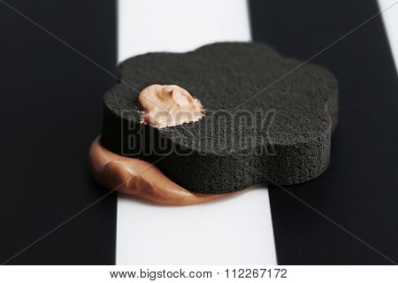 Makeup sponge with liquid foundation on abstract background