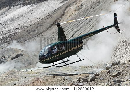 Touristic Helicopter Takes Off In Crater Of Active Volcano On Background Of Steaming Fumaroles