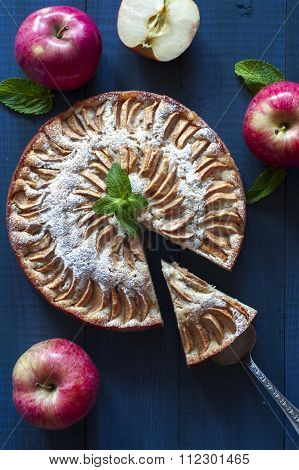 Apple pie with a piece on blue deep background