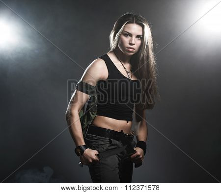 Sexy woman holding daggers with smoke. studio shot