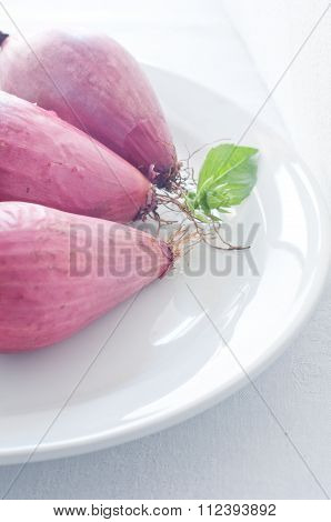 Group Of 3 Red Onions Lay On A Plate