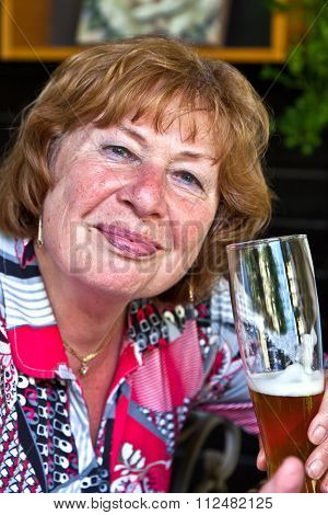 Attractive Elderly Lady Enjoys Drinking A Beer In A Beergarden