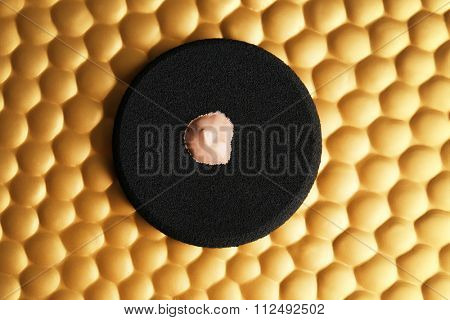 Makeup sponge with liquid foundation on abstract background