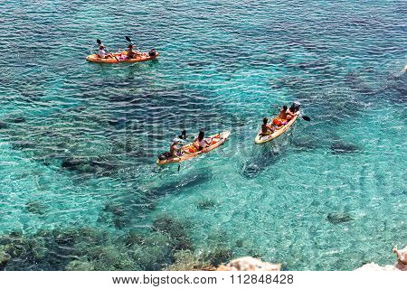 Tourists Kayaking At Tsigrado Beach In Milos Island, Cyclades, Greece