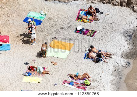 Tourists Sunbathing At The Beautiful Beach In Tsigrado Beach In Milos Island, Cyclades, Greece