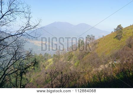 Misty mountain ridge with blue sky background.