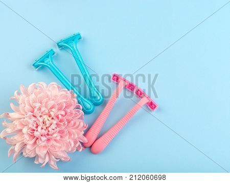Set for hair removal. Blue and pink womans razor on the blue background. Beautiful roses and pionies lying near the razors. Close-up of objects.