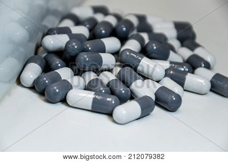 a pile of pills in the corner of the counter white background open pill bottle spilled pills and abstract angle black and white big pharma suicide rate opioid epidemic