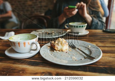 A dirty plate and an empty cup of coffee. The half-eaten cupcake on a plate. Empty dishes after eating. On the background of a girl in a cafe