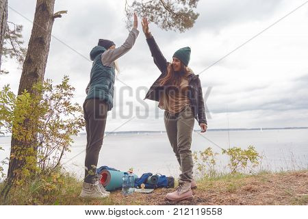 Two girlfriends travelers are proud of themselves and gave each other a high five. The concept of team success