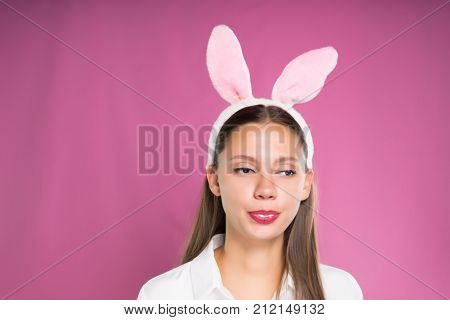 a funny girl in a white shirt and with a rim in the form of rabbit ears and chewing chewing gum