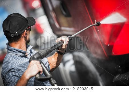 Truck Driver Washing His Semi Truck Tractor. Trucking Theme.