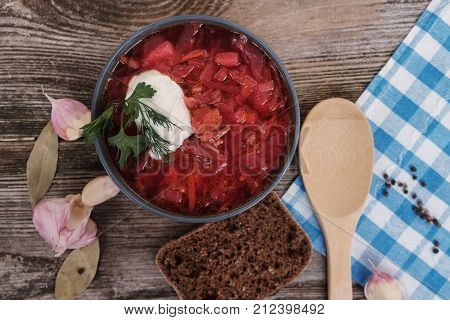 Tomato soup . Traditional Ukrainian beetroot and tomato soup - borsch in clay pot with sour cream herbs and bread on dark wooden background.