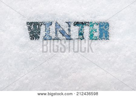 The word WINTER made from wooded letterpress letters on a snow background
