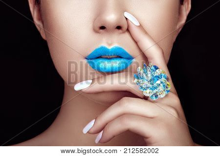 Beauty Fashion woman lips with natural Makeup and white Nail polish. Gloss Blue Lipstick. Beauty girl face close up. Sexy Lips Manicure Make up. Ring with Precious Stones Jewelry