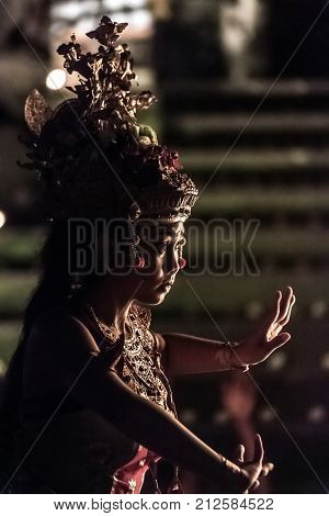 Ubud, Indonesia - August 8, 2016: Beautiful balinese woman dances during a traditional Kecak Fire Dance ceremony in Hindu temple.