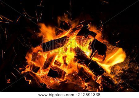 Abstract background with Burning firewood in the fireplace close up BBQ fire Sparking charcoal background. Spark of bonfire.