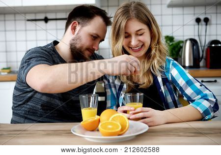 Young people drinking orange juice in kitchen.