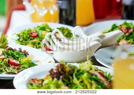 fresh salads on the plates and sause on the dinner table