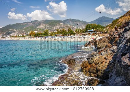 Rocky seascape of Alanya beach in Turkey on sunny summer day. Landscape of mountains and costline of blue sea. Scenery paradise lagoon bay on tropical beach.