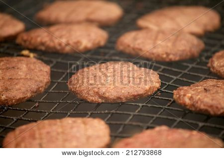 CLOSE UP OF BEEFBURGERS COOKING ON A BARBECUE