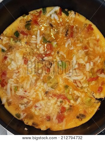 Top down closeup view of vibrant omelette being cooked in a frying pan
