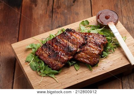 Closeup Of Pork Ribs Grilled With Bbq Sauce And Caramelized In Honey On A Bed Of Arugula. Tasty Snac