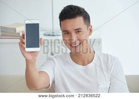 Portrait of handsome young Asian man showing smartphone