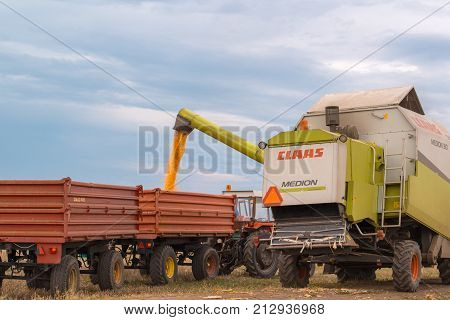 ZRENJANIN SERBIA - SEPTEMBER 19 2017: Combine harvester auger unloading harvested corn into tractor trailer. Lower maize crop yield expected this year in Vojvodina region due to drought during summer.