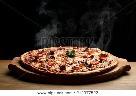Hot big pepperoni pizza tasty pizza composition with melting cheese bacon tomatoes ham paprika steam smoke on black background
