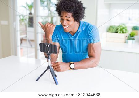 African American man doing online call with webcam using smartphone pointing and showing with thumb up to the side with happy face smiling