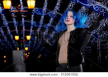 Girl With Blut Hair Skating On The Ice Arena In The Evening City Square In Winter