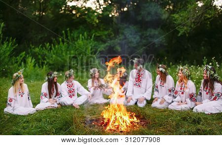 Midsummer. Young People In Slavic Clothes Sitting In The Woods Near The Fire.