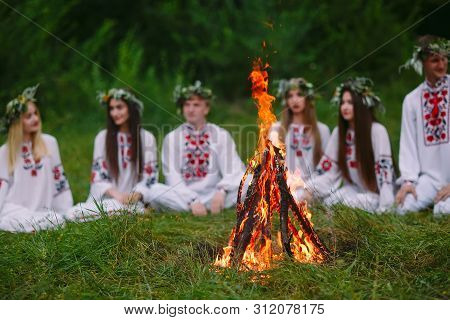 Midsummer. Young People In Slavic Clothes Sitting In The Woods Near The Fire.