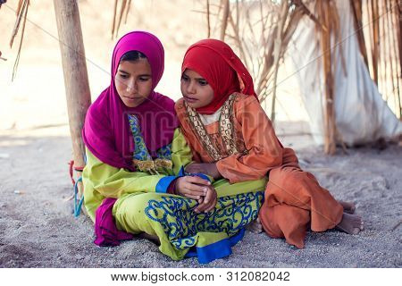 Egypt, Hurghada, 12 May 2019, Two Little Girls Sitting On The Ground In The Beduin Village