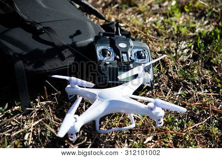 White Rc Drone And Black Controller On Grass Near Black Bag