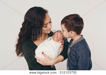 Family Photo On A White Background: Parents Spend Time With Their Children. Mom And Dad Hug The Baby