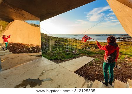 Tourist Woman With Norwegian Flag Enjoying Sea Coast View From Bukkekjerka Rest Stop Area On Andoya 