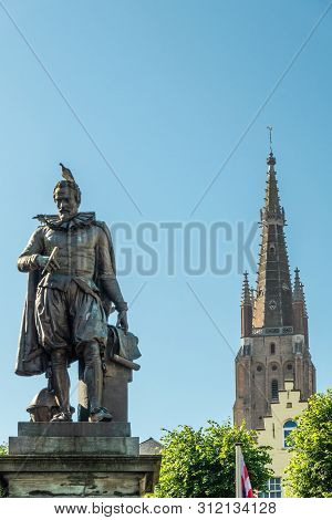 Bruges, Flanders, Belgium -  June 17, 2019: Simon Stevin Statue With Spire Of Olv Cathedral In Back 