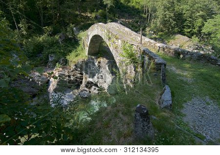 Beautiful Ancient Roman Stone Bridge Located On A Hiking Pathway Near Bignasco Village In The Beauti