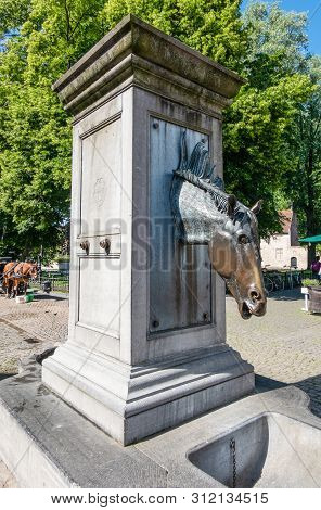 Bruges, Flanders, Belgium -  June 17, 2019: Gray Stone Water Pump With Horse Head As Faucet Especial