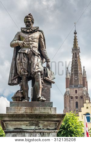 Bruges, Flanders, Belgium -  June 17, 2019: Simon Stevin Statue With Spire Of Olv Cathedral In Back 