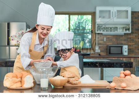 Happy Family In The Kitchen. Mother And Child Daughter Preparing The Dough, Bake Cookies