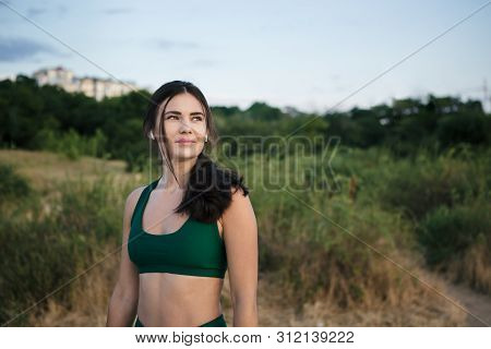 Pretty Brunette Woman Resting After Mornong Jogging At The Sea Shore At Sunrise Listening To The Mus