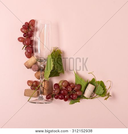 Alphabet. Letter L Made Of Wineglasses With Rose And White Wine, Grapes, Leaves And Corks Lying On P