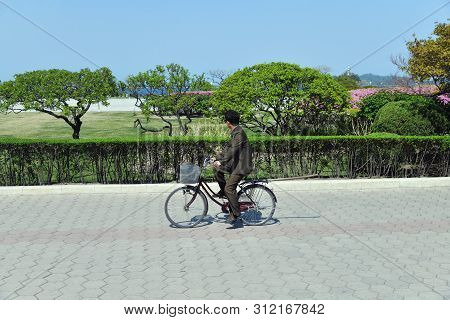 Wonsan, North Korea - May 3, 2019: Local Man On A Bike Rides Along The Sea On The Promenade Of The J