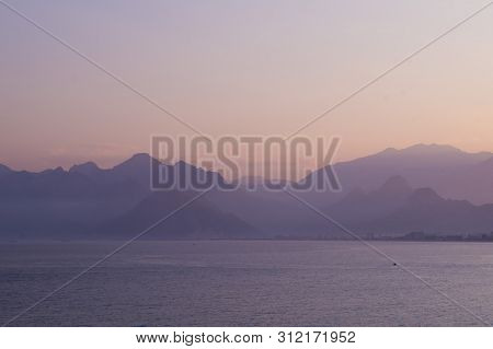 Mountains In A Blue Haze And Sunset Over The Sea